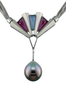 Photo courtesy Llyn L. Strelau Art deco-inspired 'Fan Dance' pendant/clasp with matte-finish platinum set with tapered baguette suite of two rubellite tourmalines (2.20 ctw), 1.03-carat aquamarine, and tapered baguette diamond suspending a 15.4 x 13.8-mm South Sea pearl with rose and aqua overtones.