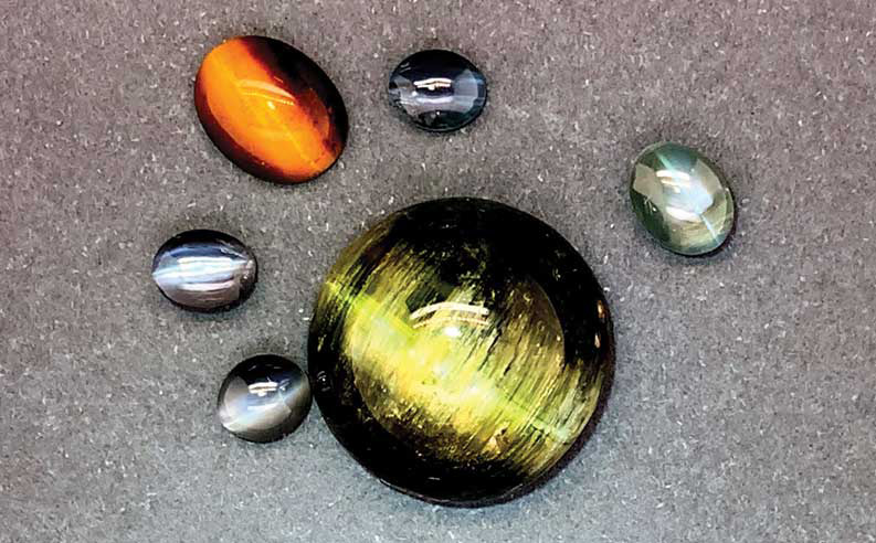 Cat’s eye phenomenon showing in a green tourmaline, a tiger eye, and some chrysoberyl.