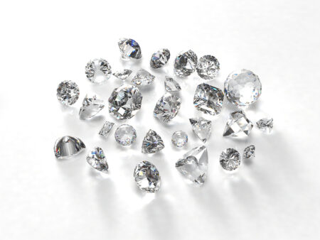 A pile of cut diamonds are in a pile on a white background.