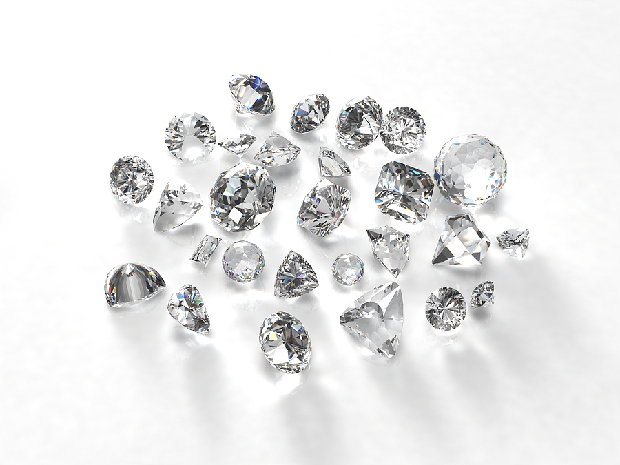 A pile of cut diamonds are in a pile on a white background.
