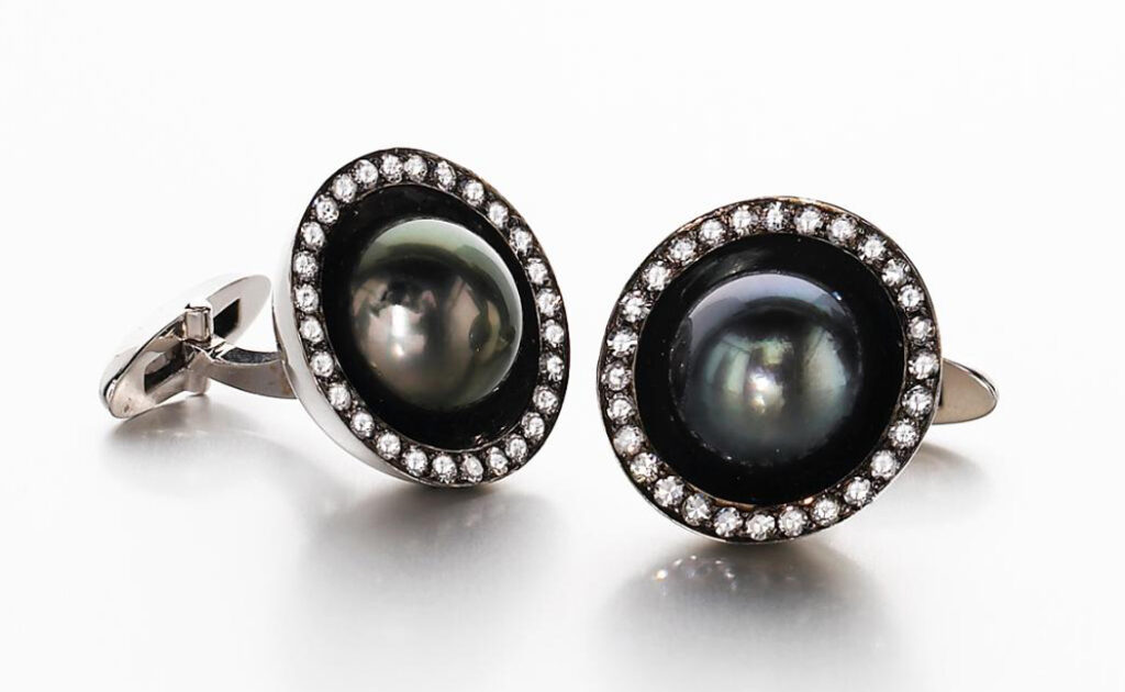 A pair of circular black pearl and diamond cufflinks on a white background.