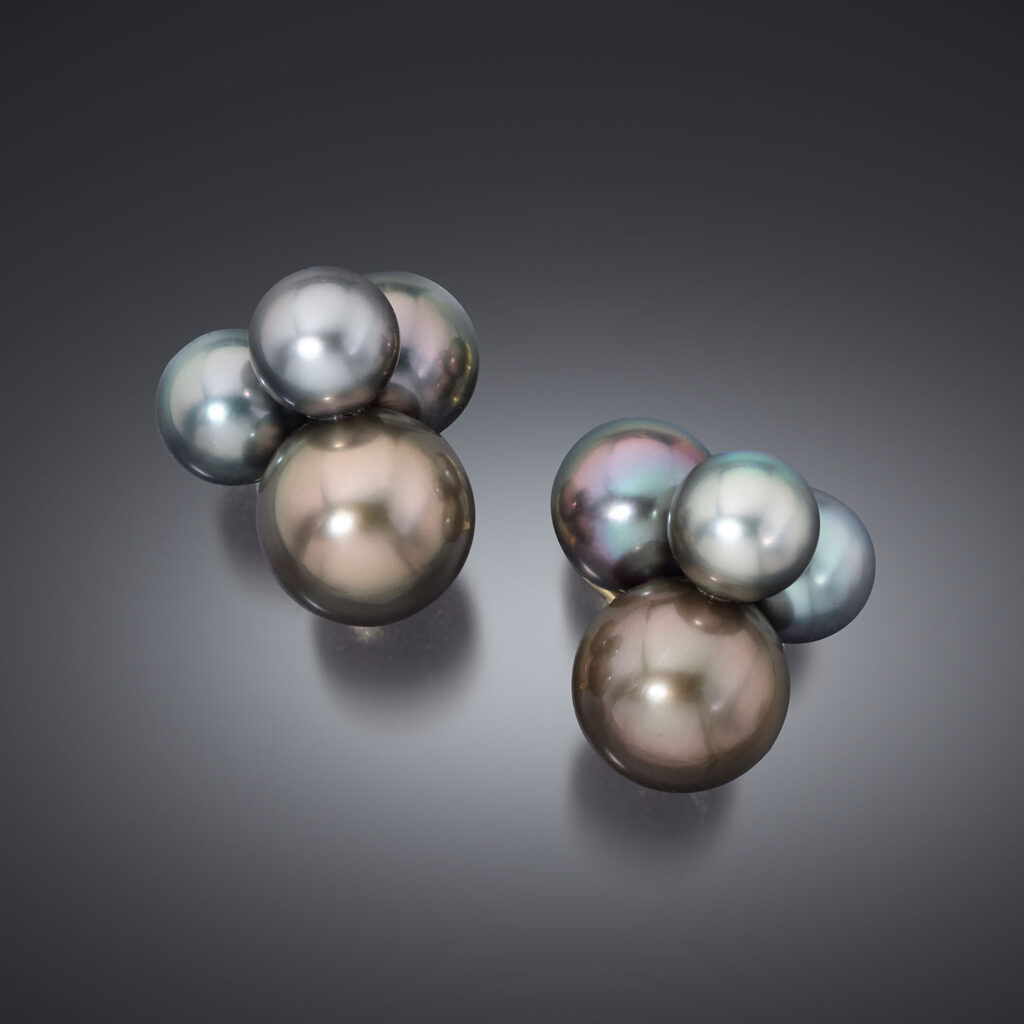 A pair of pearl earrings comprised of one large pearl and three small pearls affixed at its top.