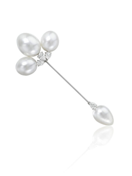 A brooch with three large pearls at the top with another pearl at the bottom on a white background.