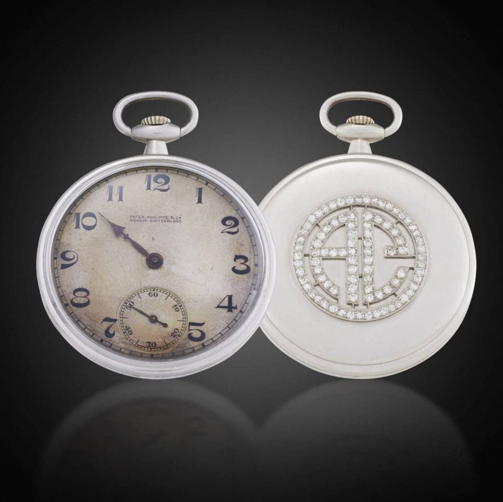 An antique pocket watch showing the case backing with the diamond-encrusted initials 