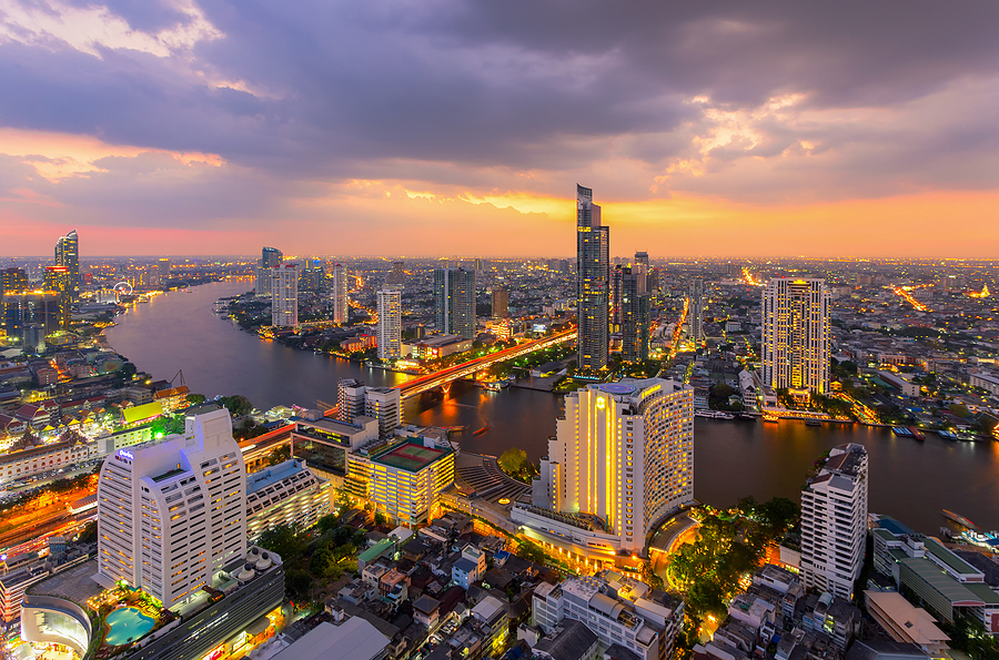 Bird's eye view of the city of Bangkok, with river running thriugh the cityscape at sunset.