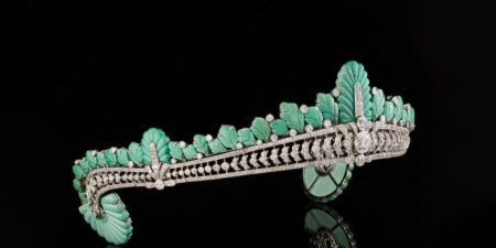 An ornate tiara adorned with turquoise and diamonds with a black backdrop.