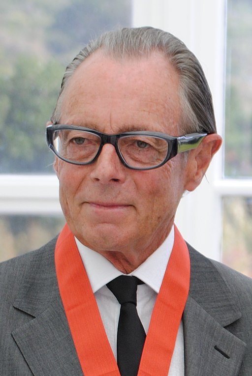 An older, white male with spectacles in a gray suit.