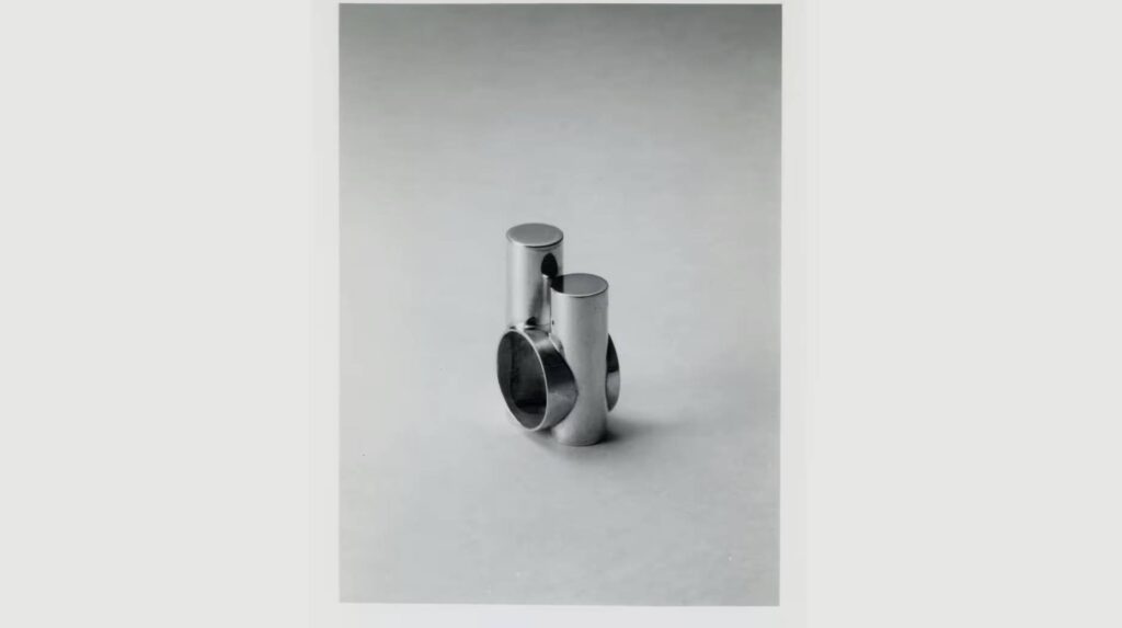 A silver abstract ring on a gray background.