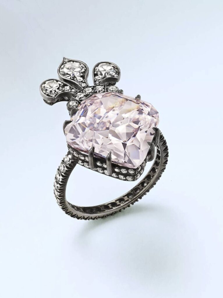 An antique diamond ring with a large pink diamond and fleur-de-lis encrusted shape.