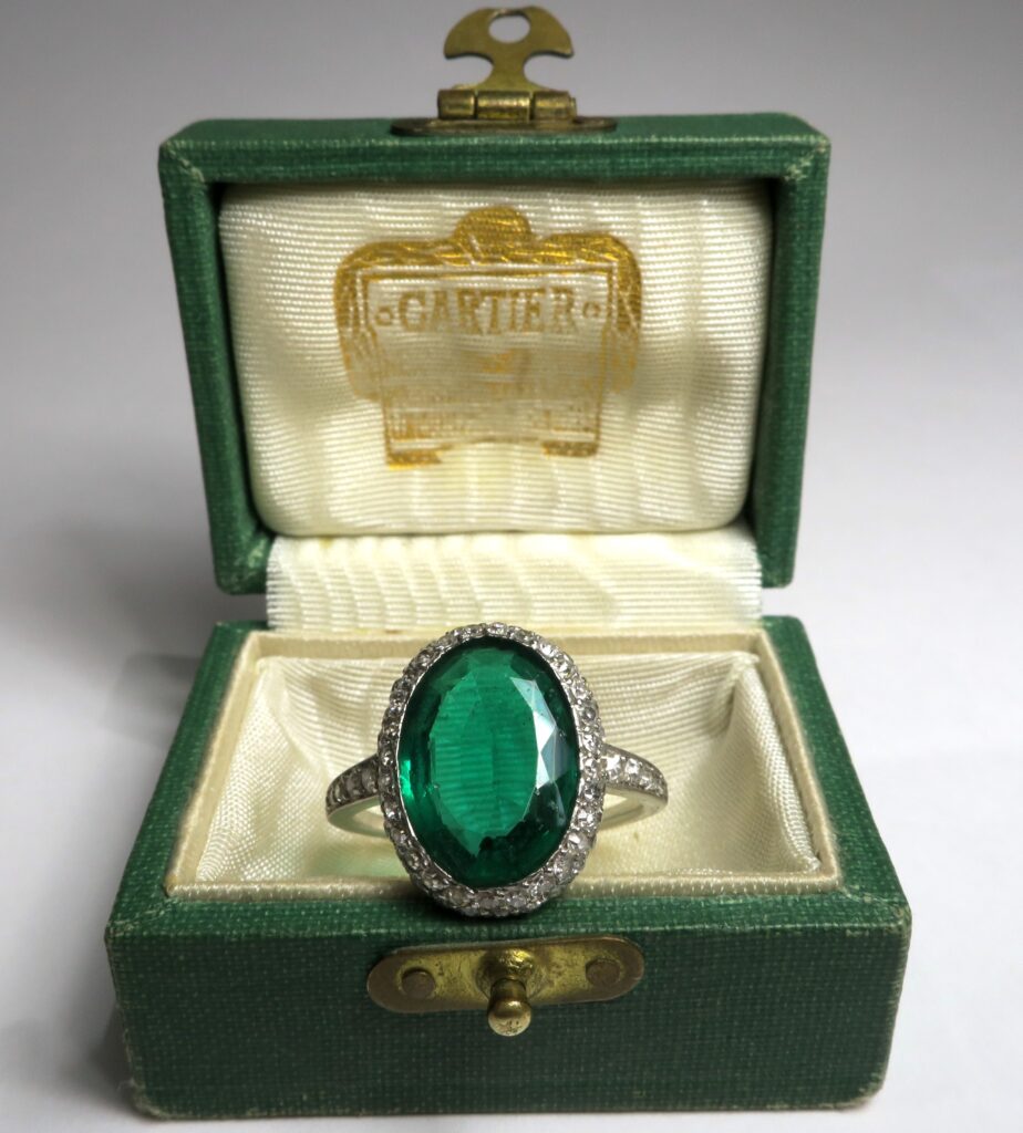A vinatge emerald ring on a ring box that reads Cartier.