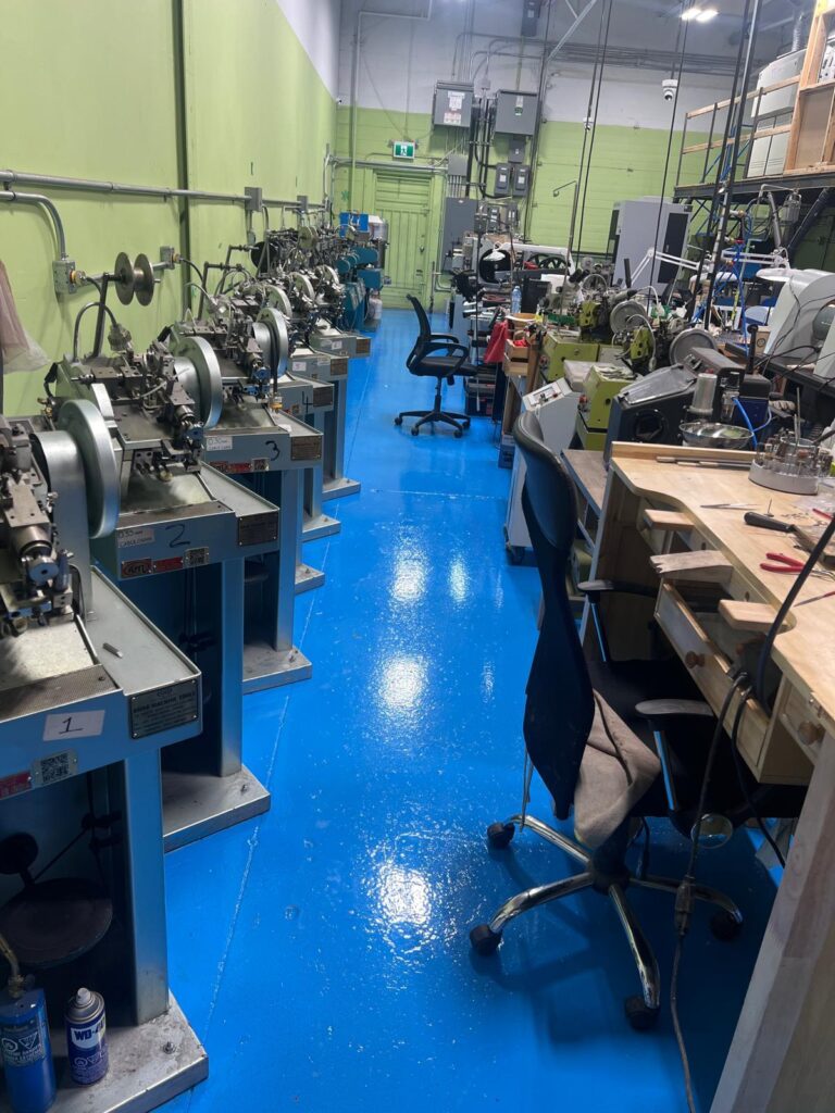 A factory facility with machinery on the left and workbenches on the right.