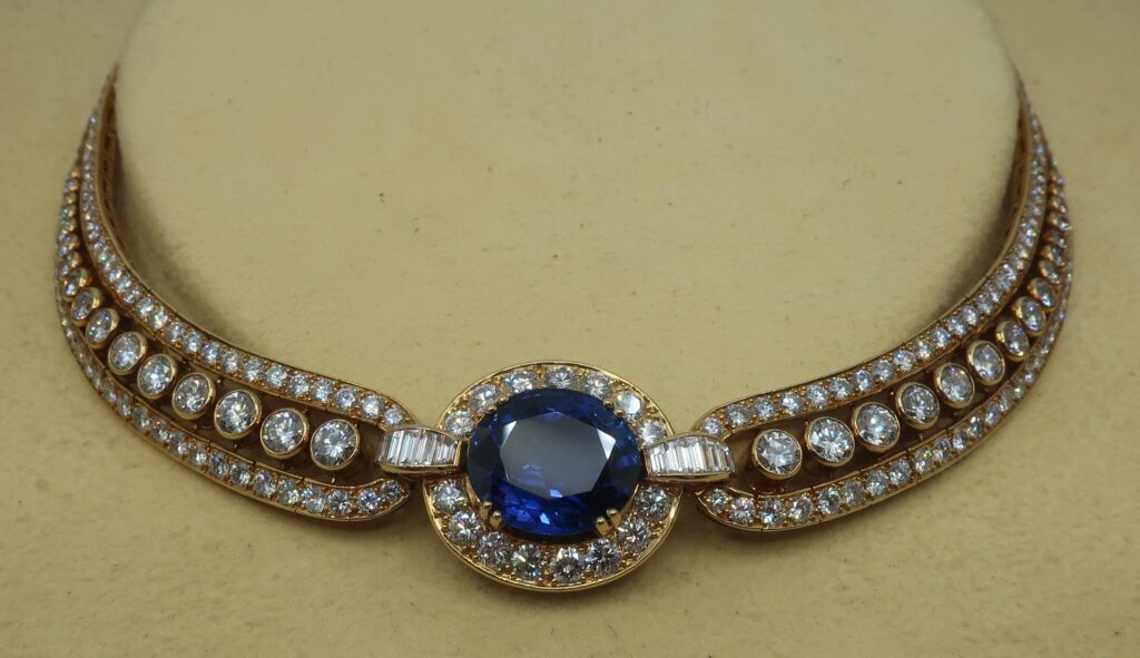 A diamond and sapphire antique necklace with a cream background.