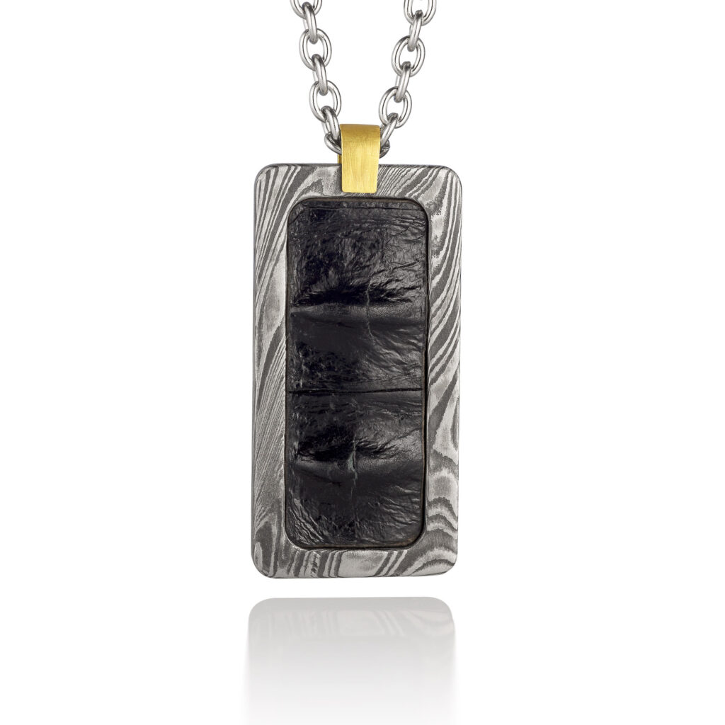 A silver and black coloured rectangular men's pendant on a white background.