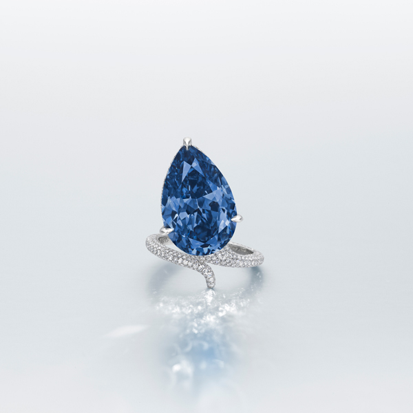 A pear-shaped blue diamond ring with a white background.