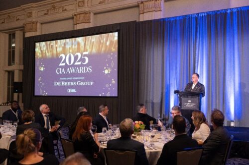 A group of business people seated at dinning tables, facing a speaker.
