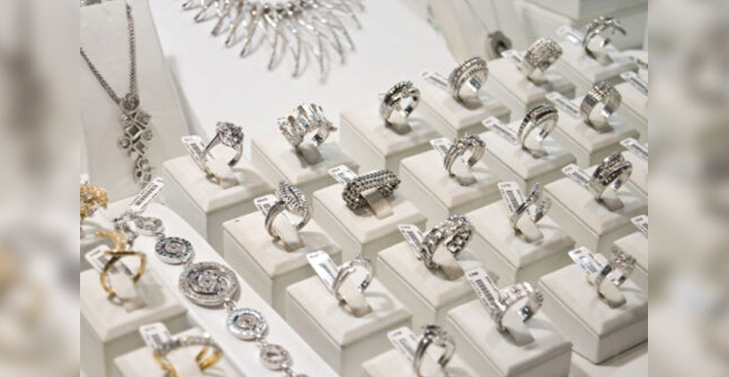 A large assortment of diamond rings are in a jewellery store display case.