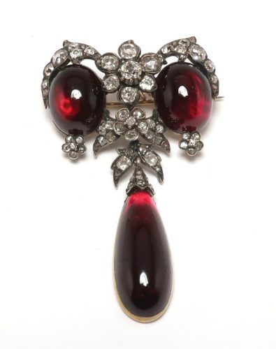 An antique diamond and garnet brooch with the diamonds set in silver.
