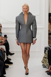 Model wearing a silver outfit that is broad in the shoulders and hips.