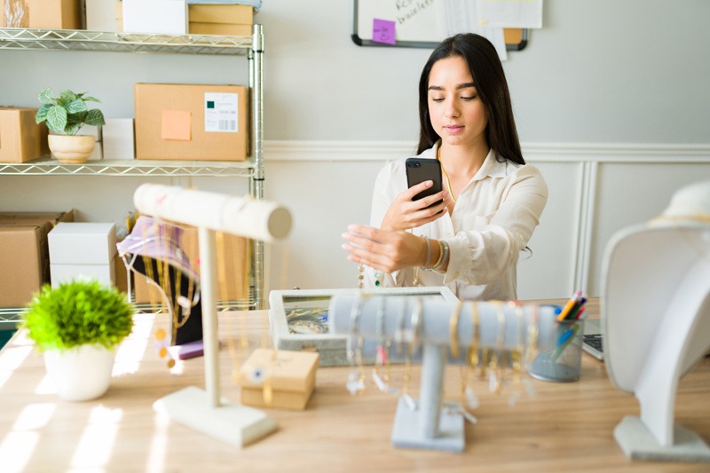 women photographing jewellery on phone
