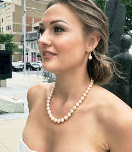 woman in a low bun and pearl necklace and earrings, looking to the side