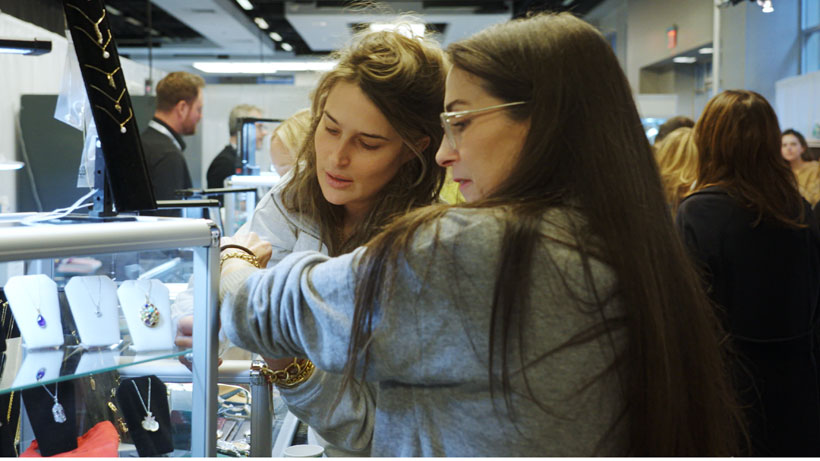 two women examining jewellery in crowded room