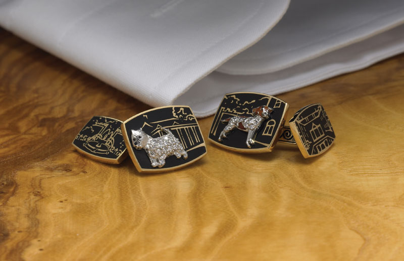 Gold and black enamel cufflinks featuring diamond-paved dog portraits against a house-and-landscape motif.