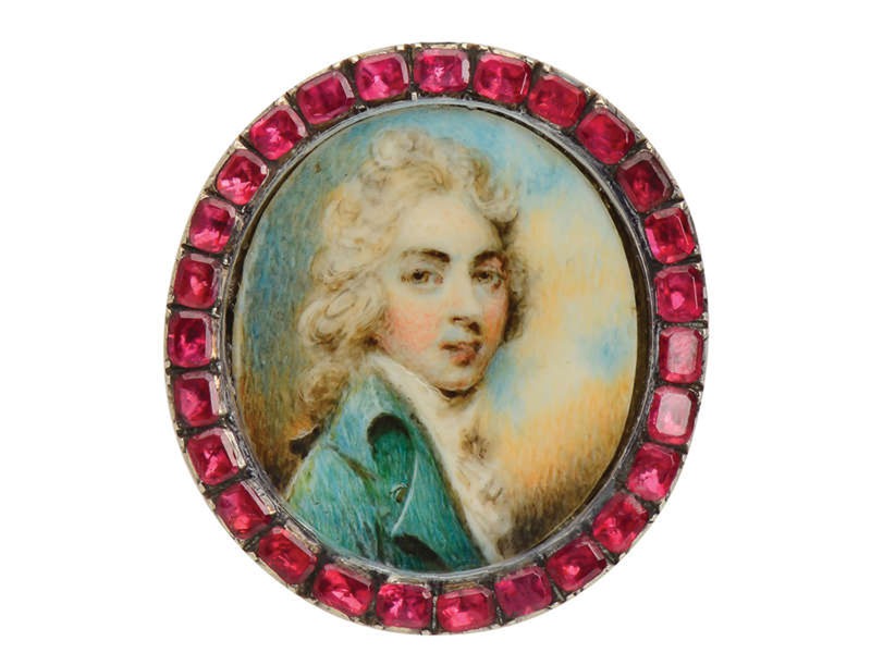 Oval miniature portrait brooch of a young man in a teal coat, framed by a border of red garnet stones.