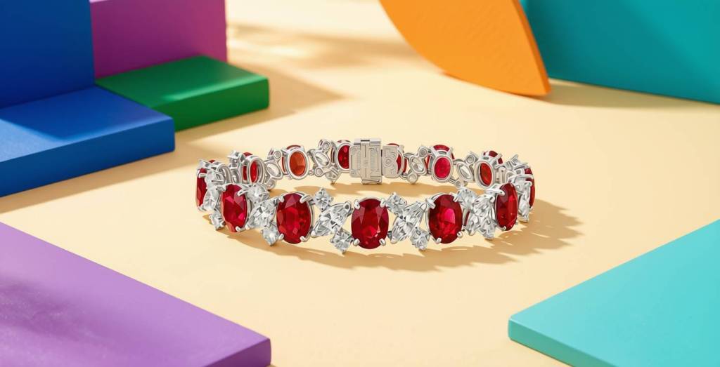 Oscar Heyman platinum bracelet featuring oval-cut rubies and marquise diamonds, displayed on a cream surface surrounded by bold, primary-colored geometric blocks in blue, purple, teal, orange, and green.